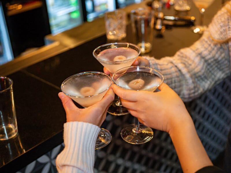 Three people clinking freshly made martinis in a cocktail making class