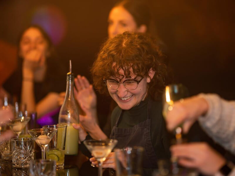 Group of women smiling as they shake up cocktails together