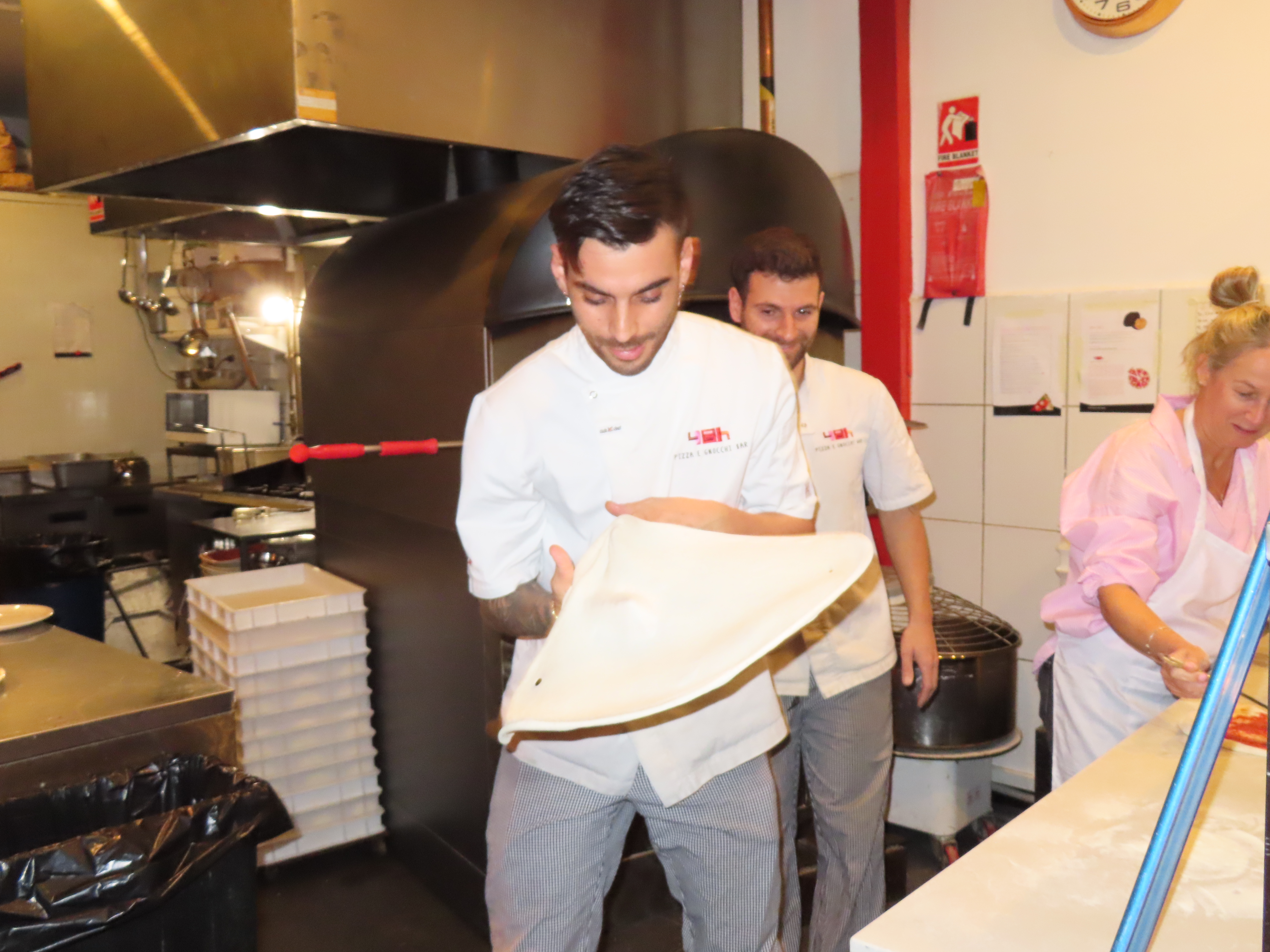A pizza chef in chef's whites tossing dough