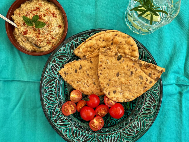 A plate of flatbread and tomatoes on an aqua coloureed table