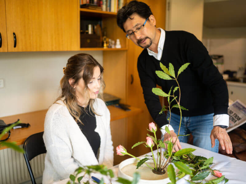 An ikebana teacher inspecting a student's work
