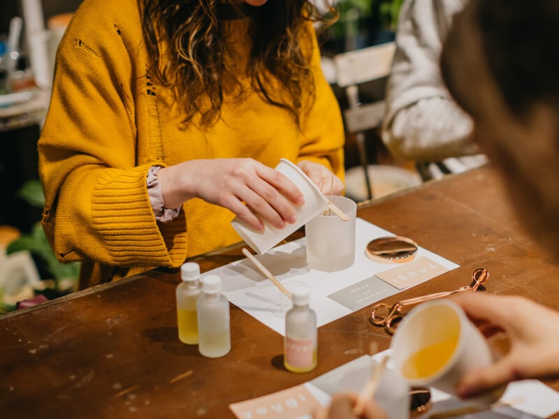A woman pouring wax into a soy candle jar.