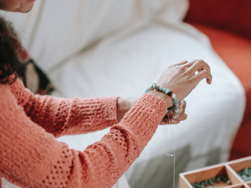 A woman tries on a beaded DIY bracelet)