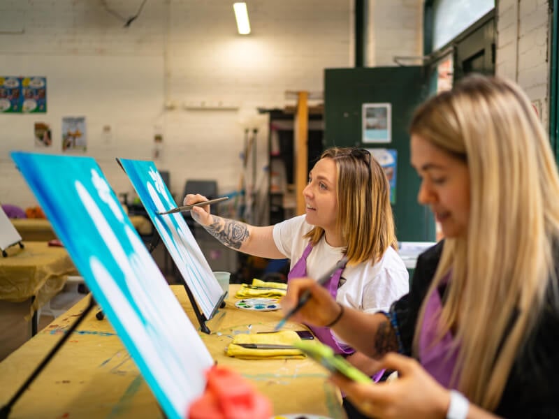 Two women enjoy a painting class