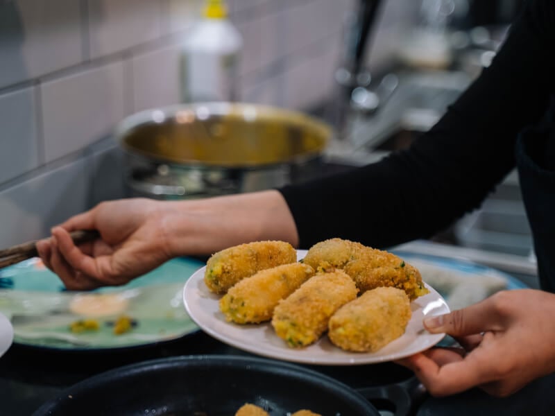 A hand holding a plate of croquettes at a cooking class