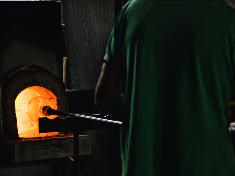 A man holding a glassblowing pipe