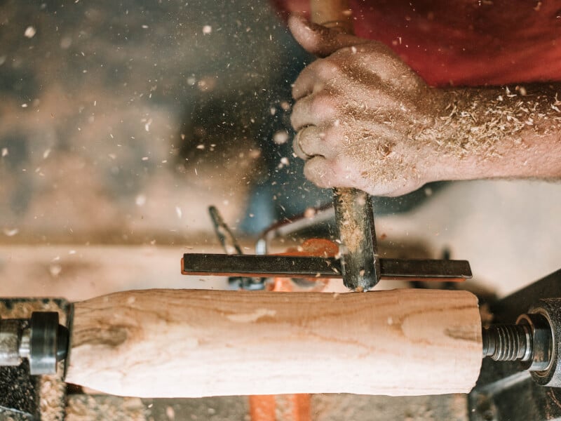 A person does some woodwork with a tool