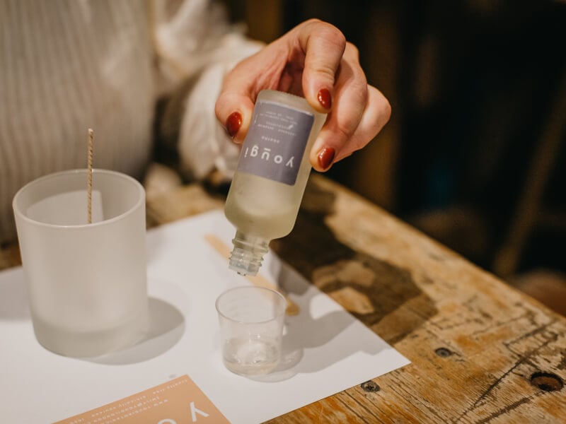 A woman pouring fragrance oil into a small jar