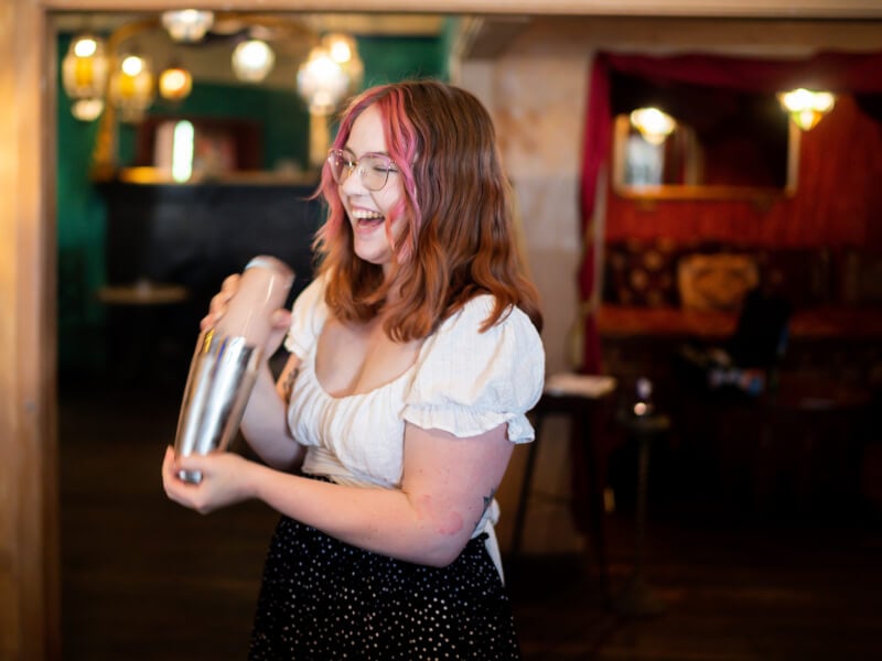 Woman shaking cocktail shaker at a cocktail class