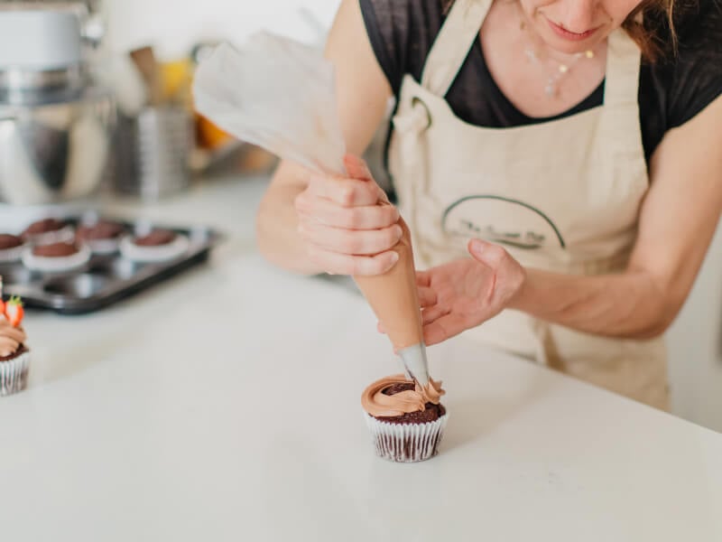 A closeup of a chocolate cupcake being iced.