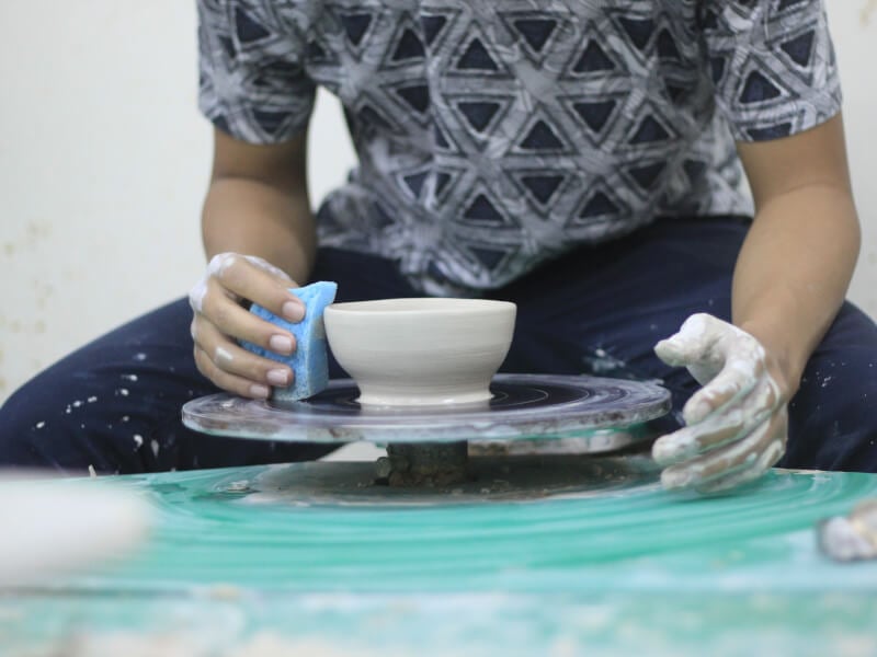 Someone tries wheel throwing and makes a clay bowl