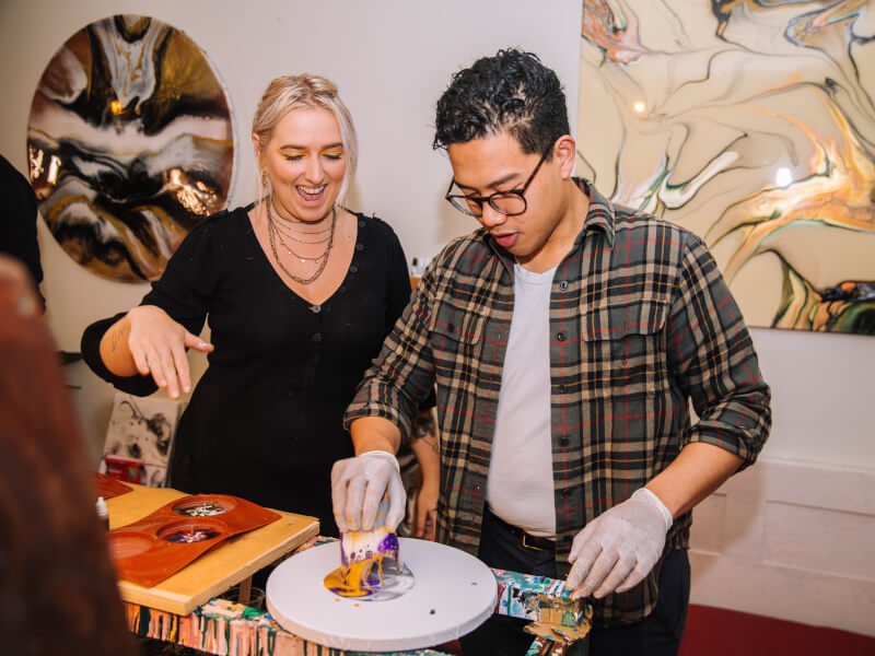 A man creating colourful fluid art on canvas