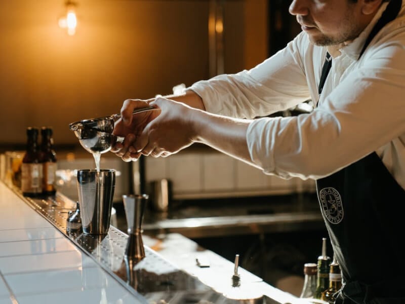 Person squeezing juice into a cocktail shaker