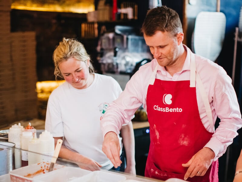 A man and woman at a pizza making class