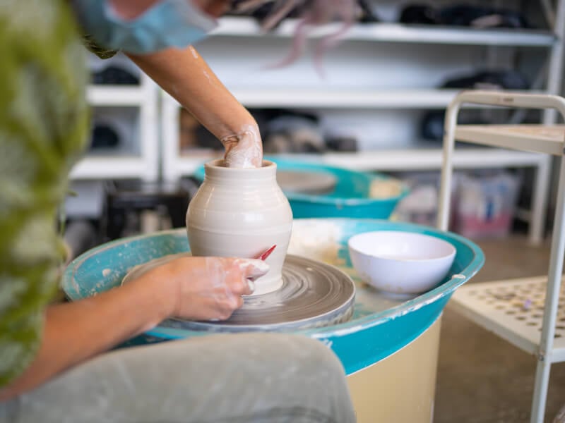 A person at making pottery at a wheel throwing workshop.
