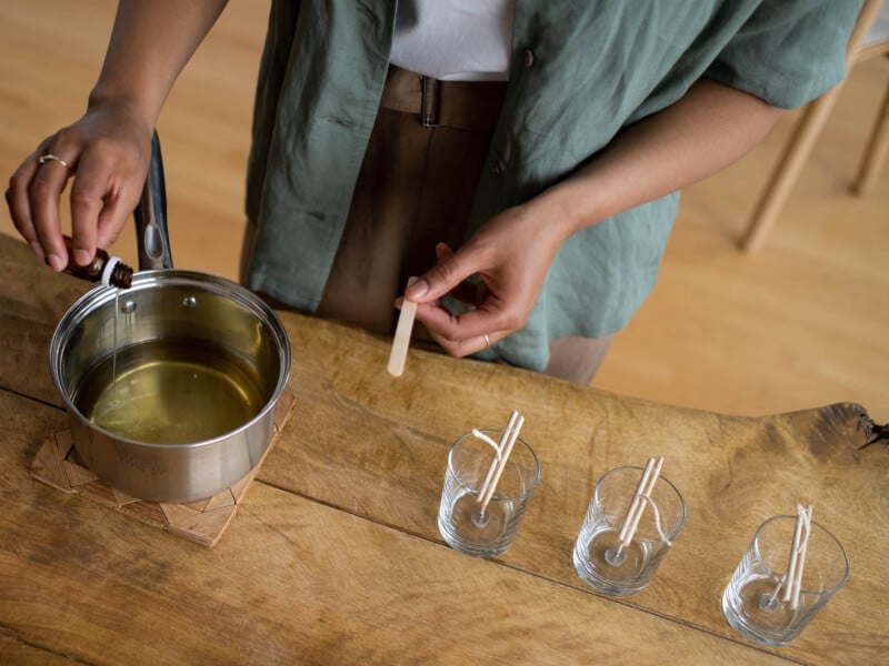 A woman pouring oil into melted wax