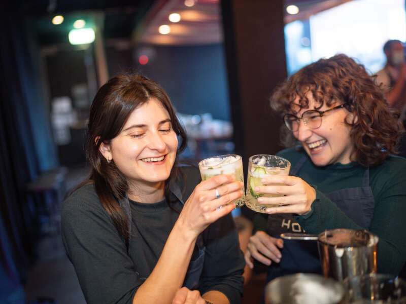 Two people clinking their cocktails at a cocktail class for two