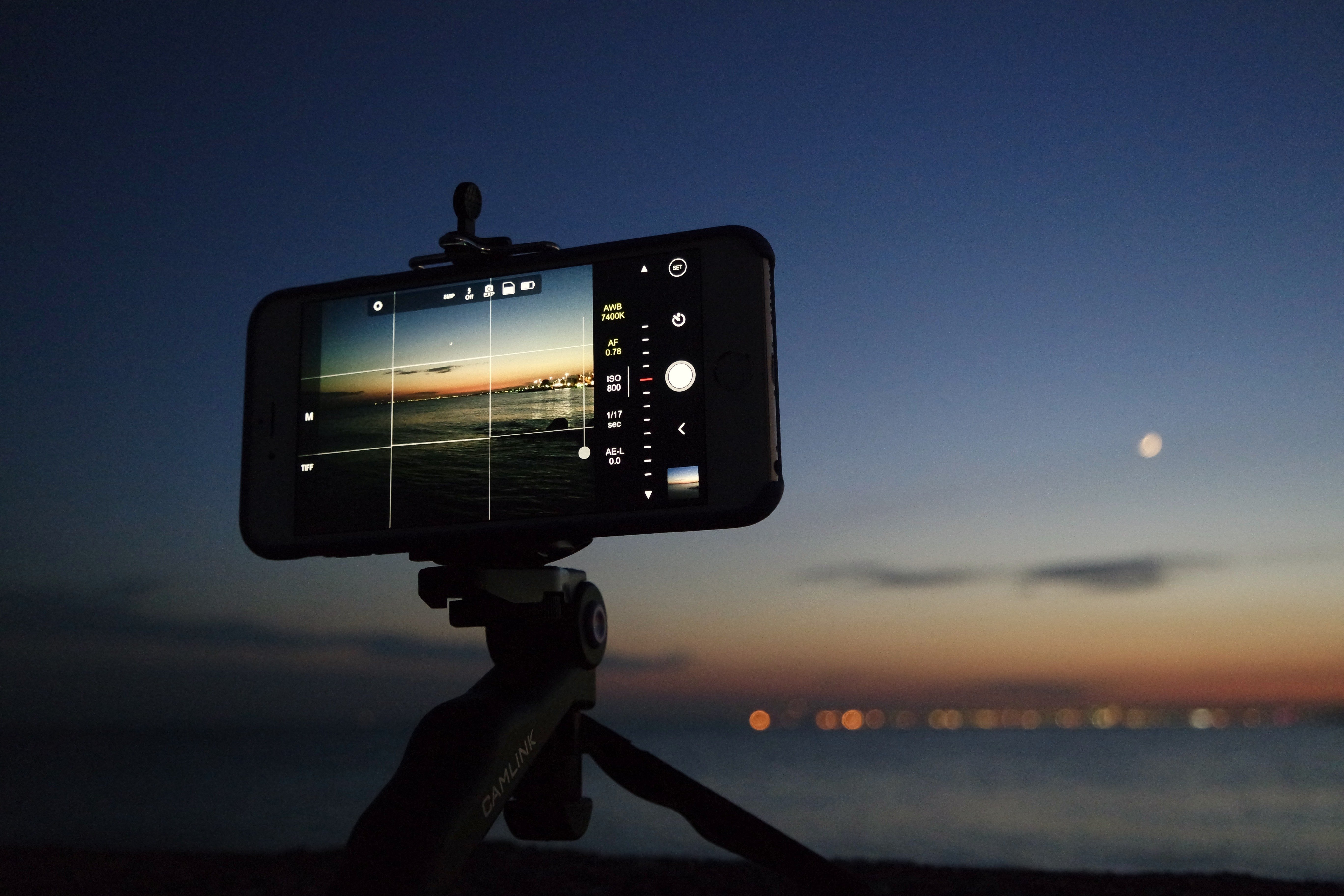 A smartphone on a tripod framing a picture of a city at night