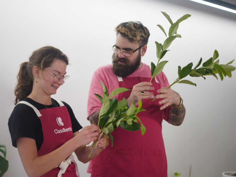 Man and woman holding plants at a floristry class.