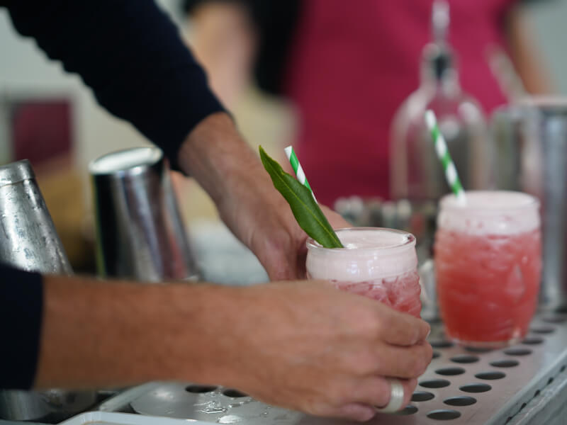 A hand holding a pink DIY cocktail with a green garnish. 