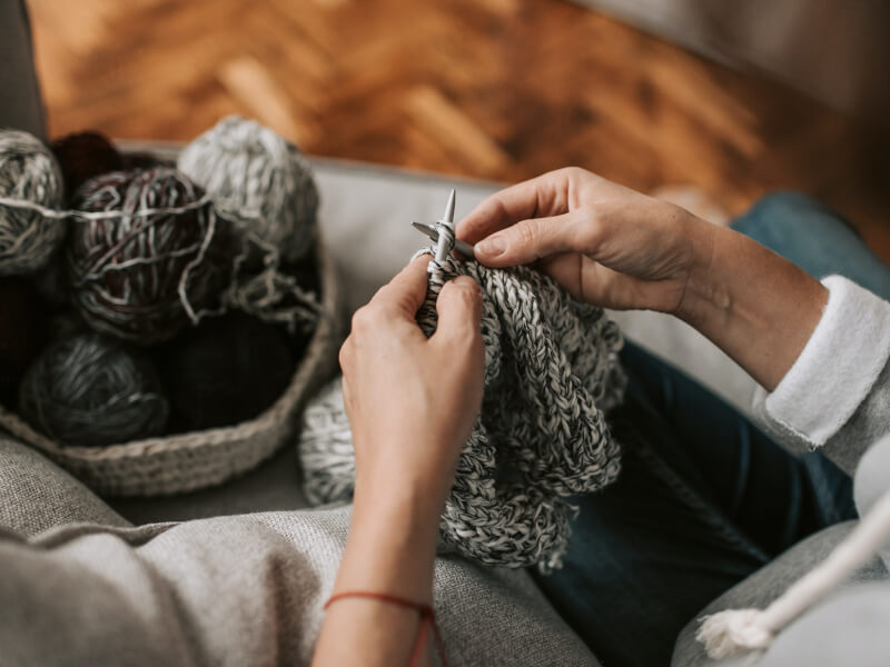 A close up of a person knitting with black and white streaked yarn