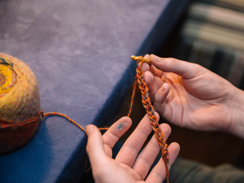 A close up of a person holding a length of crochet chain stitch in multicoloured yarn