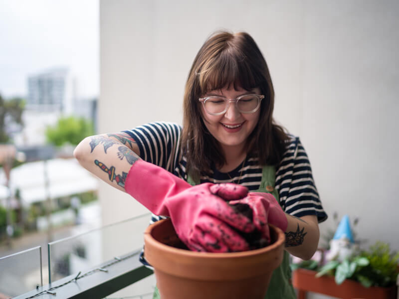 Person wearing pink gloves making a kokedama moss ball