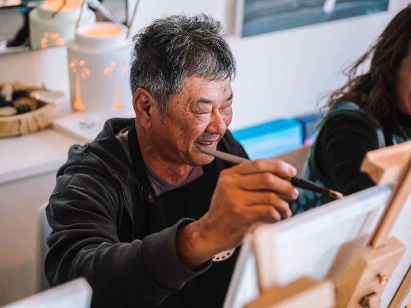 A smiling man painting on an easel