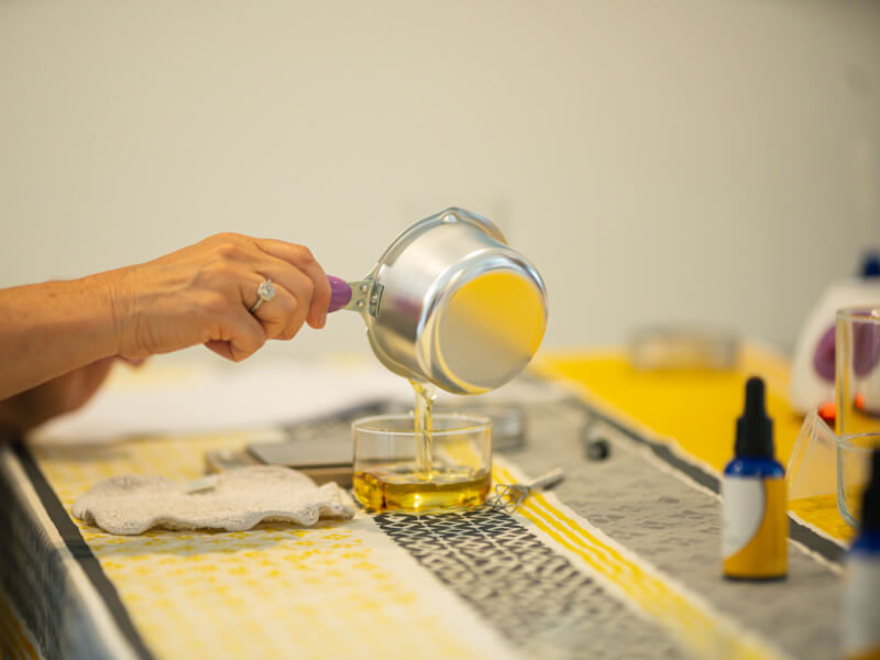 Someone pouring melted wax into a container