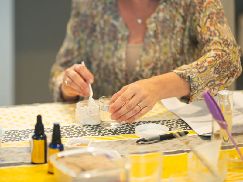 A woman sitting at a table making DIY skincare products