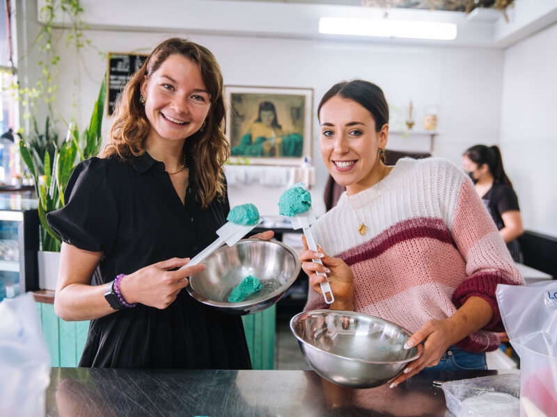 Two people smile and hold up spatulas at their baking class.