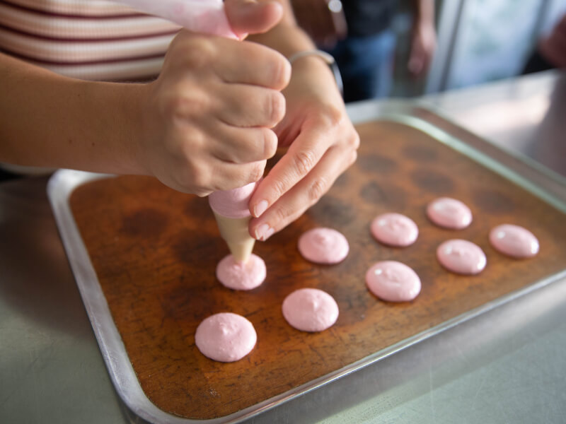 A closeup of a woman piping onto a tray.