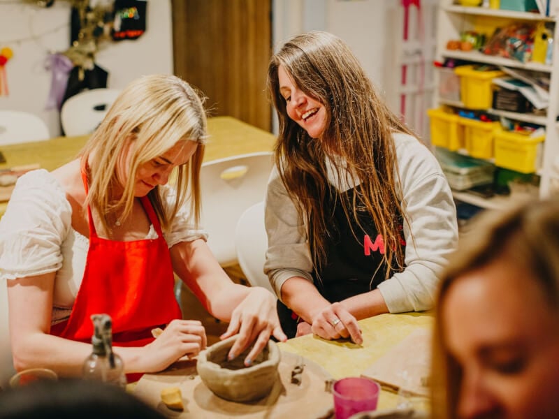 Two women laughing at a pottery class together