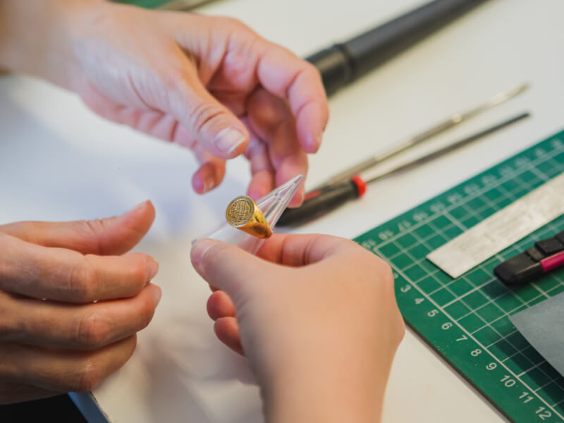 A close up of a person holding a gold ring on a ring sizing tool