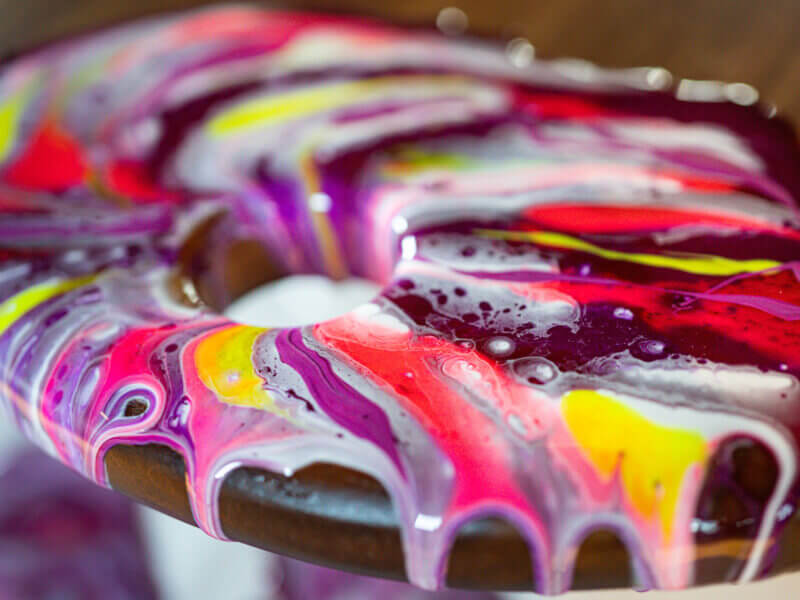 A picture of a chopping board decorated in bright colours using the paint pouring technique