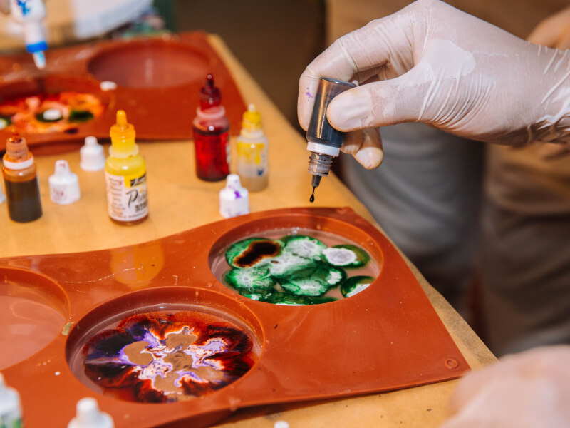 A person is mixing acrylic paint colours at a paint pouring art class