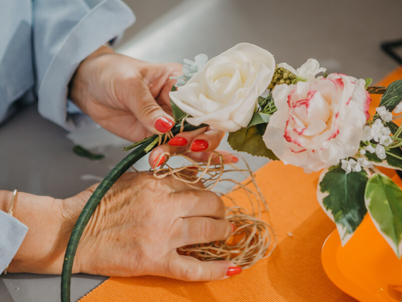 A close up of a person making a floral hoop from pink and white flowers and greenery