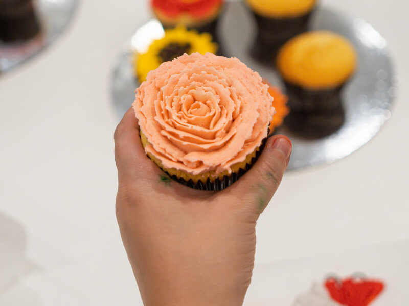 A child's hand holding a decorated cupcake.