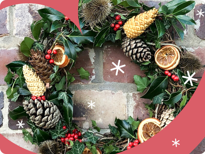 a festive wreath hanging against a brick backdrop