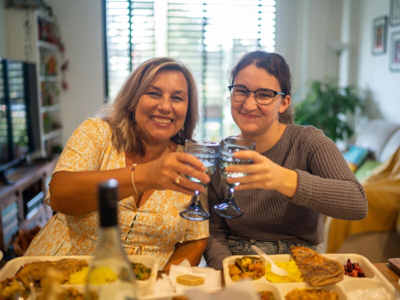 Two women are clinking glasses at an Indian cooking class