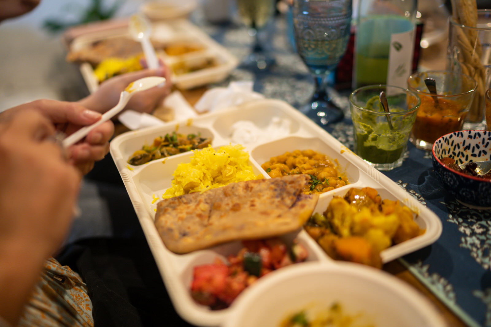 A row of thali trays filled with a variety of Indian dishes