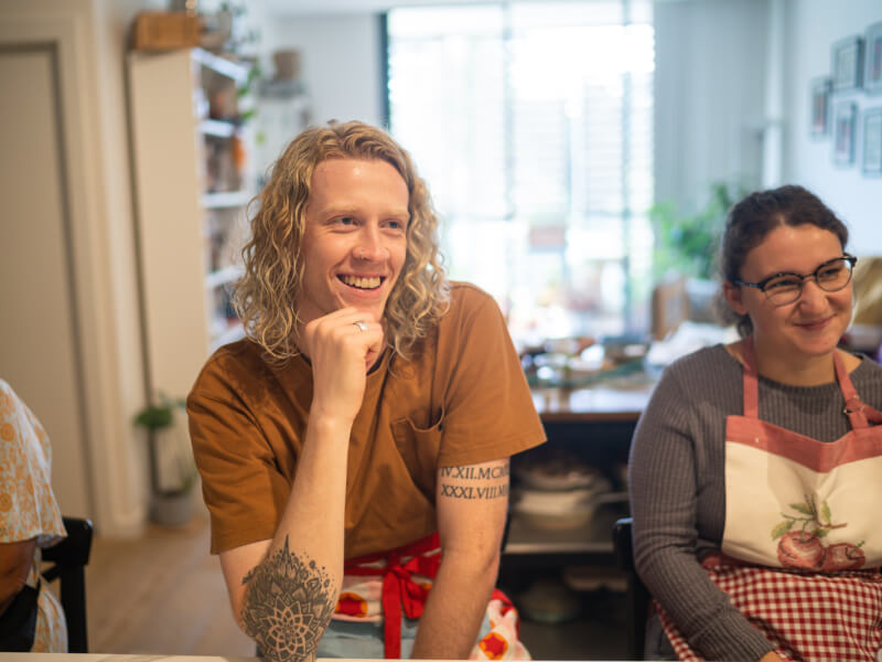 A couple smiling wearing aprons at a cookery class
