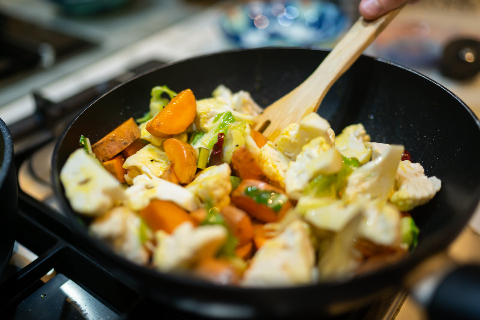 A person stirs a pan full of diced vegetables