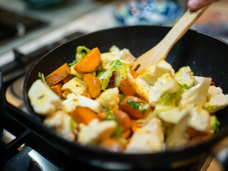 A closeup of vegetables being stirred in a pan.