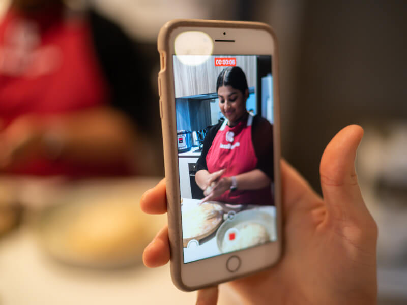 Someone taking a picture of a person at a cookery class.