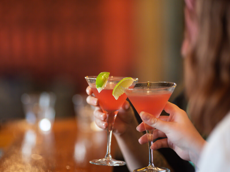Two women drinking pink cocktails at a hen party.