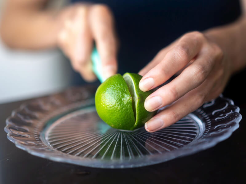 Close up of hands cutting a fresh lime