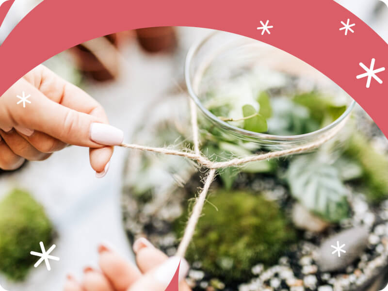 A person tying string around a DIY terrarium.