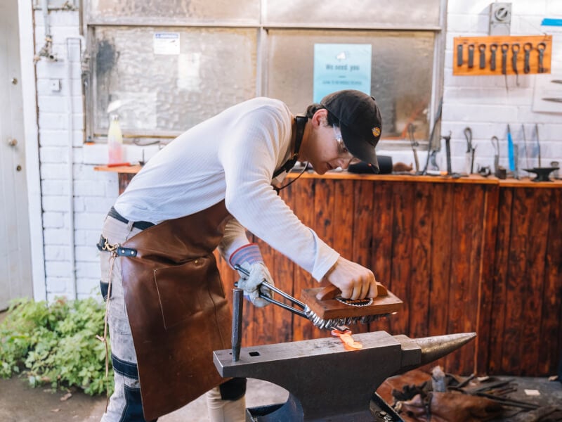 A person working at an anvil at a blacksmithing class