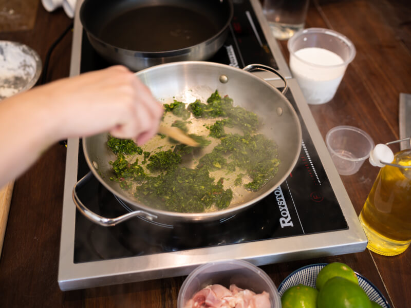 A person stirring food in a pan at a cooking class.